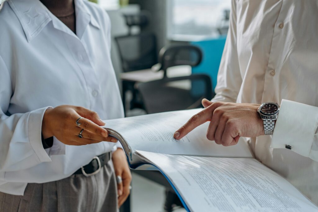 pexels-photo-8297478-8297478 Two business professionals discussing and reviewing documents in a modern office setting.
